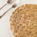 Detailed close-up view of a natural woven straw placemat, rustic kitchen table decor. - Diameter 18-20cm