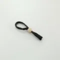 Detailed view of the black woven napkin ring showcasing the wooden bead and tassel detail. - Water Hyacinth Polygon Wooden Bead Napkin Rings