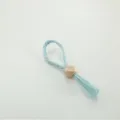 Light blue woven paper napkin ring with a wooden hexagonal bead, simple tabletop decor item for dining. - Dyed Water Hyacinth Napkin Ring with Wood Beads