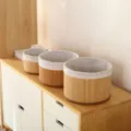 Detailgezicht van ronde gewoven opbergmanden met stoffen voering op houten kast. - Ronde set van 3