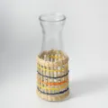 Handgemaakte glazen fles met een natuurlijke geweven strohoes voor huisdecoratie - Melkfles