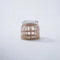 Glass bottle detail view with handmade woven straw net cover and metal handle. - Style 10