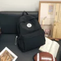 Großer schwarzer minimalistischer Rucksack für Damen und Studenten mit stilvollem runden Aufnäher. - L / Schwarz