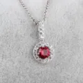 Detailopname van een zilveren hanger halsketting met rode steen en sprankelende zirconia. - Rood