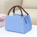 Blauw-wit gestreepte geïsoleerde lunchtas met bruine handvatten voor dagelijks gebruik. - Blauw gestreepte lunchtas