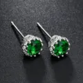 Nahaufnahme der eleganten Kronen-Ohrstecker mit funkelnden grünen Zirkoniasteinen im Detail. - Grün