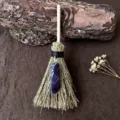 Nahaufnahme Detail eines Miniatur Hexenbesen Hängeornaments mit natürlichem Lila Kristall und Stroh. - Besen mit Amethyst