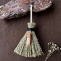 Dettaglio della mini scopa della strega con paglia naturale e ciondolo in cristallo arancione. - Scopa + Avventurina Rossa