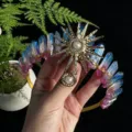 Closeup detail of natural crystal crown headband featuring sunburst metal accessory and sparkly stones. - Blue Red Gold Sun
