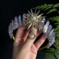 Detail view of crystal crown headband featuring purple quartz pillars and sun goddess metal motif. - Light Purple Gold Sun