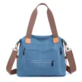 Casual blue canvas tote bag with brown straps and functional front zipper pockets for daily use. - Blue