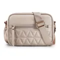Close-up view of the beige quilted crossbody bag featuring a soft leather front pocket and strap. - Khaki