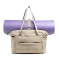 Gedetailleerd overzicht van de beige canvas tote tas met een vaste paarse yogamat. - camel