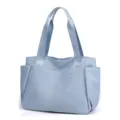 Detail view of the light blue lightweight nylon tote bag showing dual fabric handles and exterior pockets. - Sky Blue