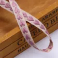 Close-up detail of woven ribbon with embroidered hearts, ideal for gift packaging and DIY crafts. - Deep Pink