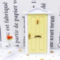 Détail de porte d'entrée de maison de poupée, porte jaune cadre blanc accessoires dorés. - Jaune