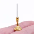Macro detail shot of a miniature golden dollhouse candlestick and white candle prop. - Gold