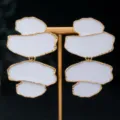 Vue détaillée de boucles d'oreilles géométriques irrégulières à l'huile blanche et bords dorés. - Blanc
