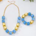 Gros plan sur le collier et bracelet de perles géométriques en acrylique bleu et or, été. - Bleu