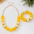 Primo piano dettaglio del set collana e bracciale in blocchi geometrici acrilici gialli. - Giallo