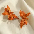Gros plan sur les boucles d'oreilles fleur orange rétro avec bords dorés. - Style de Fleur (JMX-ER9585) / Orange