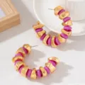 Gros plan sur les boucles d'oreilles créoles en C avec des perles dorées et perles violettes. - Rose