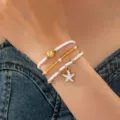 Gros plan d'un bracelet de perles multicouche avec des pendentifs coquillage et etoile de mer. - Parure de Bracelet (JMX-SL9648)