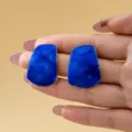 Gros plan détaillé des boucles d'oreilles clous émaillées trapèze bleu irrégulier, texture brillante. - Bleu foncé
