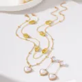 Gros plan du collier double doré style rétro français et de ses boucles d'oreilles nacrées. - Ensemble boucles d'oreilles + collier / Blanc