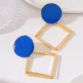 Gros plan détaillé de boucles d'oreilles géométriques creuses dorées et émail bleu raffiné. - Style Losange Creux Multi-Couches Rond Émail (JMX-ER9789) / Bleu
