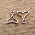 Detailaufnahme silberner, hohler Walflossen-Anhänger, ideal für DIY-Schmuck und Bastelarbeiten. - Weißgold