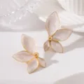 Gros plan detaille de boucles d'oreilles fleuries dorees avec une texture emaillee. - Blanc (JMX-ER9497)