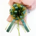 Close-up detail of green and gold tree grain gift pull bow, perfect for wedding car and decor. - Green