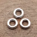 Primo piano di perline distanziatrici tonde argentate e anelli metallici per gioielli. - Argento antico