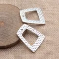 Nahaufnahme von silbernem gehämmertem geometrischem Trapez Hohl DIY Anhänger Zubehör Detail. - Weißgold