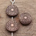 Gros plan détaillé de perles rondes en cuivre antique avec motif floral gravé. - Cuivre rouge antique