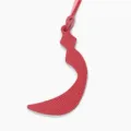 Detailed view of red textured leather Arabic letter shape bag charm, stylish accessory. - Red