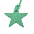 Gros plan détaillé d'un charm de sac en cuir vert en forme d'étoile avec sa lanière assortie. - Vert