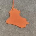 Leather map bag charm detail shot showing orange texture and hanging strap close up. - Orange