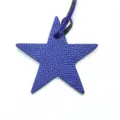 Vue rapprochée détaillée du charm de sac en cuir étoile violette avec une lanière. - Bleu