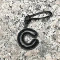 Detailed view of the black leather letter C bag charm, highlighting its fine texture. - Uppercase Letter C / Black