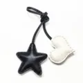 Gros plan détaillé du charm de sac en cuir étoile et cœur avec coutures fines et lanière. - Cœur Blanc Cassé avec Étoile Noire