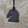 Vue détaillée du charm de sac tête de cheval en cuir noir, montrant la texture et la lanière. - Noir