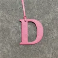 Pink leather letter D bag charm detail shot, elegant handbag accessory with strap ornament. - Pink