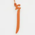 Detailed close-up view of the orange leather Arabic letter bag charm with matching cord. - Orange