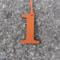 Orange leather number 1 bag charm detail shot, stylish DIY accessory close-up display. - Orange