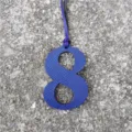 Close-up detail of the blue leather number 8 bag charm pendant with fine hanging strap. - Sapphire Blue