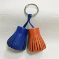 Dual-color leather tassel charm detail view, showing blue and orange leather fringes and ring. - Orange and Royal Blue