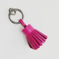 Primer plano de llavero con borla de cuero genuino, anillo metálico elegante y accesorio. - Rosa rojo