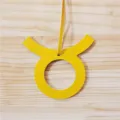 Detailed close-up of the yellow leather Taurus zodiac bag charm pendant showing fine texture. - Yellow